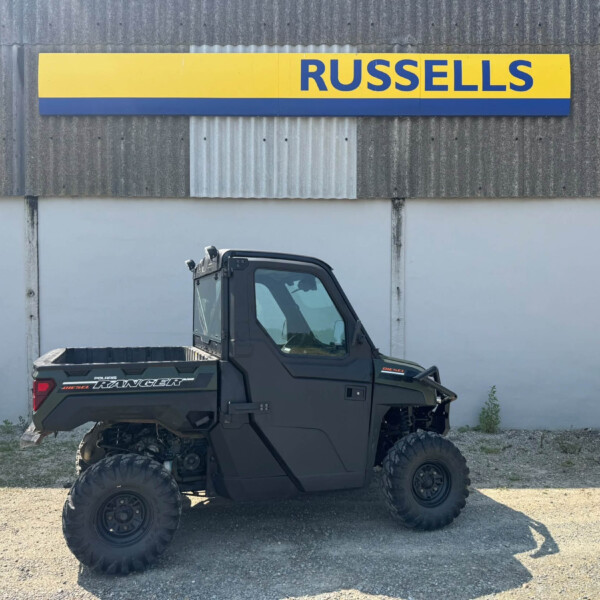 Black Polaris Ranger Diesel UTV parked outdoors in front of a yellow-and-blue building sign that reads 'RUSSELLS'