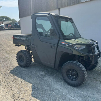 Diesel Polaris Ranger off-road utility vehicle in the foreground on a gravel lot, with tractors and farm equipment visible in the background.