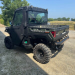 Black Polaris Ranger Diesel side/rear view parked on a gravel path with countryside fields in the background.