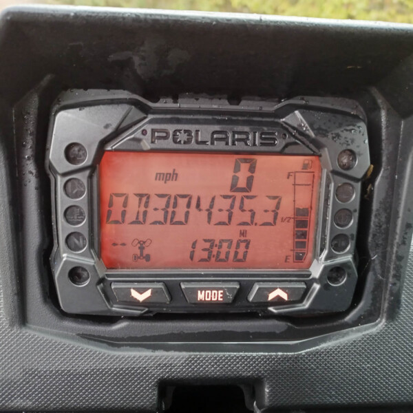 Polaris instrument cluster with a red backlit digital display showing speed in mph and status indicators inside a protective housing.