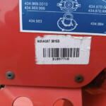 Close-up of a red machine with a blue diagram label and a white barcode sticker reading NOVACAT 301ED underneath.