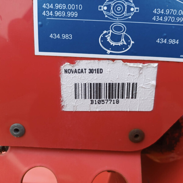 Close-up of a red machine with a blue diagram label and a white barcode sticker reading NOVACAT 301ED underneath.