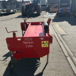 Red Spiker 1350 machine in an outdoor equipment yard with tractors and trailers nearby.