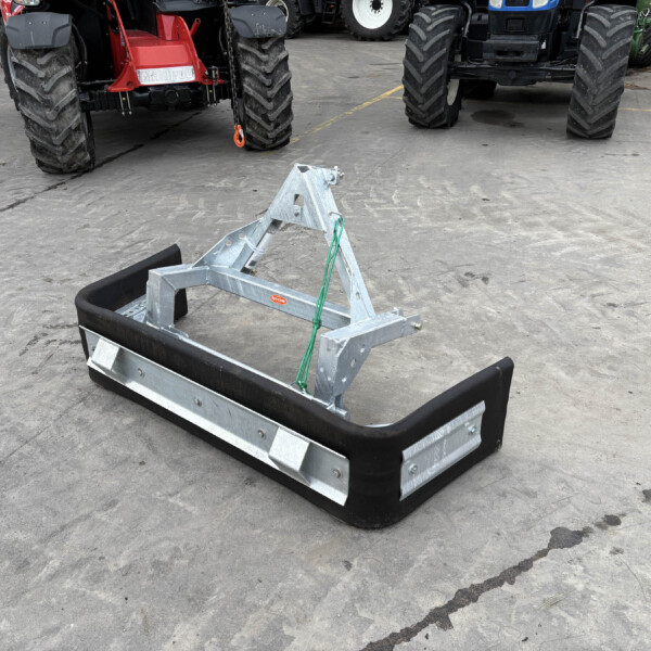 Industrial trailer attachment in foreground on a concrete lot with large tractors in the background