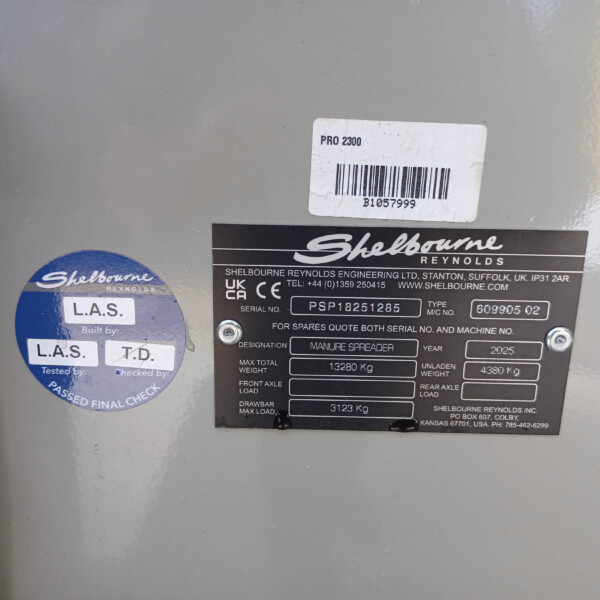 Close-up of a metal machine surface with labels: 'PRO 2300' barcode sticker and Shelbourne Reynolds plate, plus a blue circular badge.