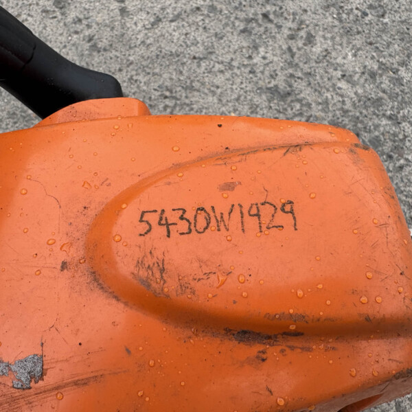 Close-up of an orange plastic tool housing with a black grip and water droplets on its surface.