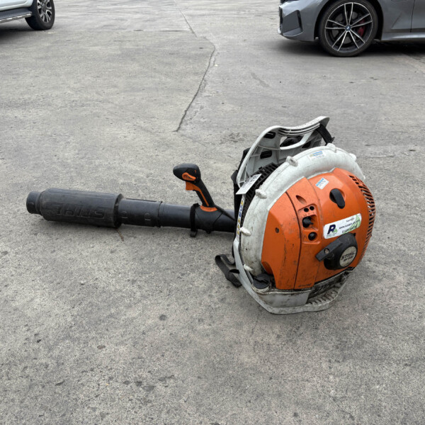 A concrete cut-off saw lying on its side in a parking lot with two cars in the background.