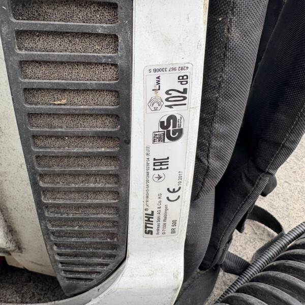 Close-up of a dusty metal panel with a vertical sticker displaying CE markings and model numbers near black vent slats.