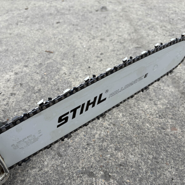 Close-up of a chainsaw bar and chain on a rough concrete surface, showing STIHL branding.