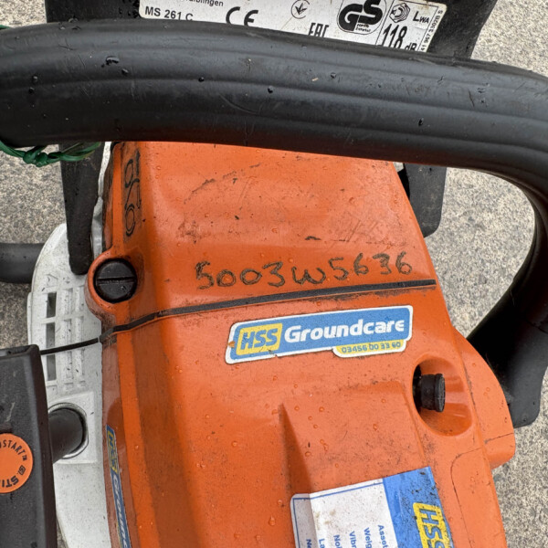 Close-up of an orange gardening tool with a coiled black power cord and HSS Groundcare sticker.