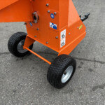 Orange industrial cart with four wheels on a gray asphalt surface.