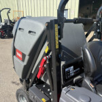 Close-up of a Toro skid-steer loader with hydraulic lift arm and safety labels, parked outside a warehouse.