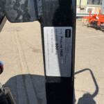 Close-up of a metal identification plate on a dark beam, showing weight info (800 kg) with an outdoor construction background behind it.