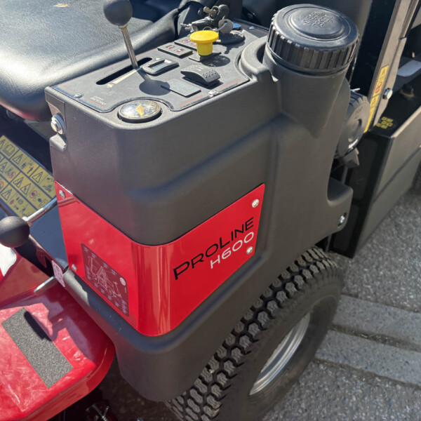 Close-up of a red lawn tractor control panel with a gear lever, ignition, and yellow safety cap.