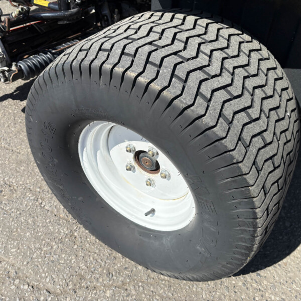 Close-up of a large off-road tire mounted on a heavy vehicle, showing the rugged tread and wheel hub with bolts.