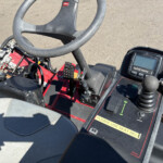 Close-up of a tractor cockpit showing the steering wheel, InfoCenter display, and a 'Please use seat belt' label nearby.