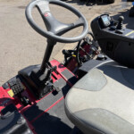 Close-up of a tractor cab interior showing the steering wheel, joystick, and control panel.