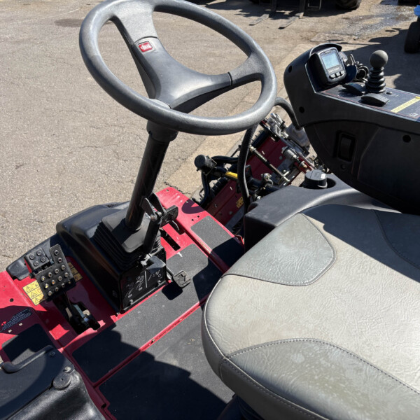 Close-up of a tractor cab interior showing the steering wheel, joystick, and control panel.