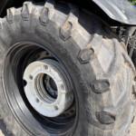 Close-up of a large agricultural tractor tire with deep, aggressive tread and a white metal rim