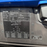 Close-up of a black data plate on a blue vehicle showing Valtra safety structure details and weight specifications.