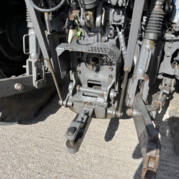 Close-up of a rusted tractor/industrial machine's control panel and hydraulic components.