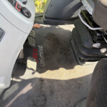 Driver’s footwell with two metal pedals and a black, dirty floor mat beside the seat