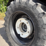 Close-up of a large tractor tire with deep treads and a white, rusted rim.