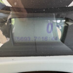 Close-up of a car dashboard screen displaying a large purple '0', with dust and reflections on the glass.