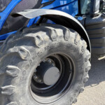 Close-up of a large off-road tractor tire beside a blue tractor body panel.