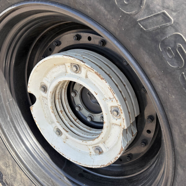Close-up of a large tire with a rusted white wheel hub and visible lug nuts.