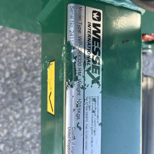 Close-up of a green industrial device showing a metal nameplate with model/serial information and peeling labels.