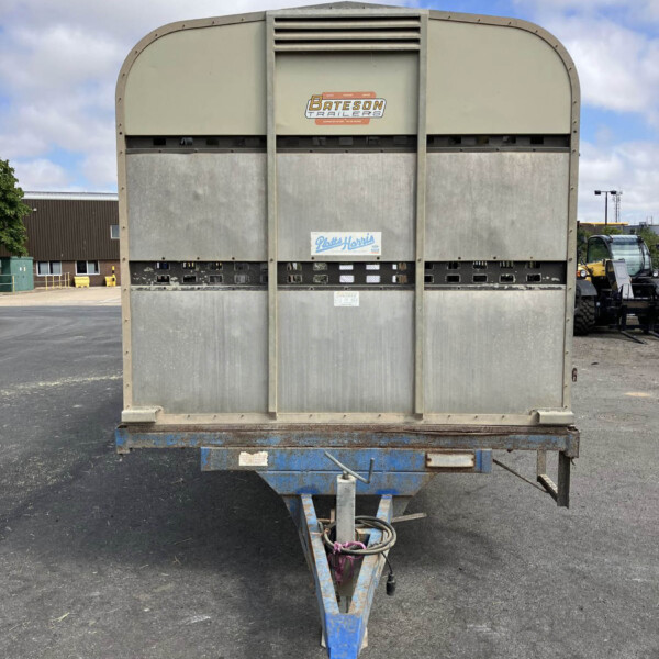 Rear view of a large beige trailer on a blue hitch, with a Bateson Trailers logo visible, in a parking lot.
