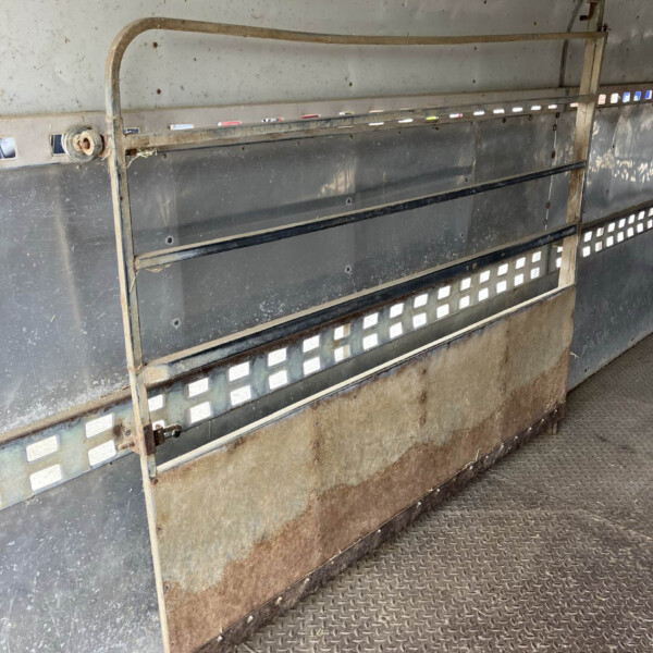 Rusty metal trailer interior with weathered panels and a dirty, diamond-plate floor edge.