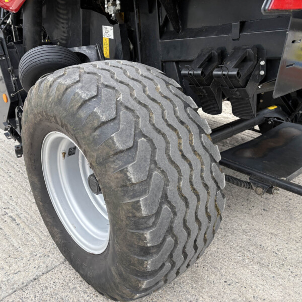 Close-up of a large off-road tire on a heavy-duty vehicle, with black chassis and mechanic components in the background.