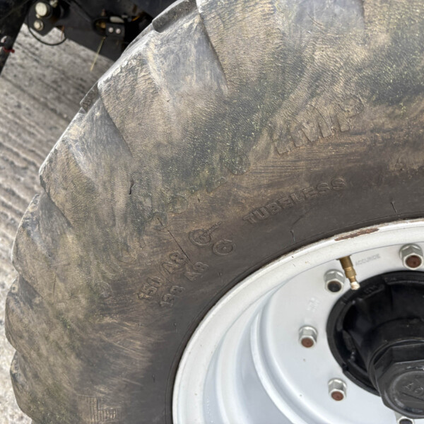 Close-up of a muddy motorcycle tire and rim with dirt on the tread and wheel bolts visible.