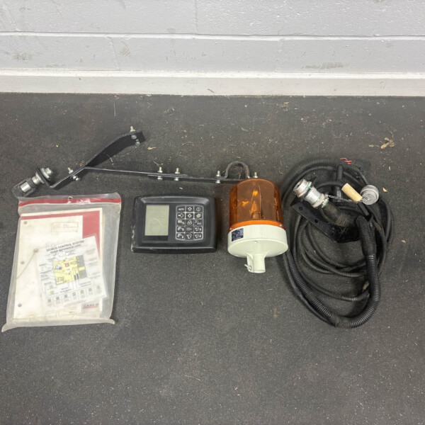 Automotive control panel with display, orange beacon, mounting hardware, and tangled cables on a concrete floor surface.