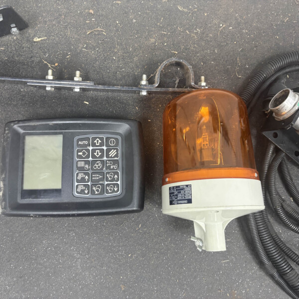 Top-down view of a control panel with keypad and a large orange warning beacon surrounded by wires and a black surface surface edge.