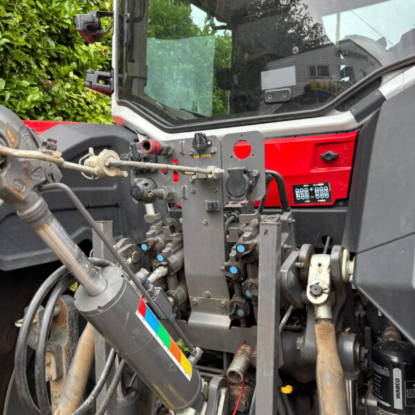Close-up of a heavy machinery cab interior showing hydraulic valves, levers, and wiring around the operator area.