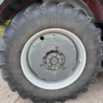 Close-up of a large tractor rear tire and wheel, showing the bulky tread and metal rim with a green center plate under a red fender.