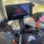 Interior of a tractor cabin with a tablet displaying the Massey Ferguson logo and controls around the screen