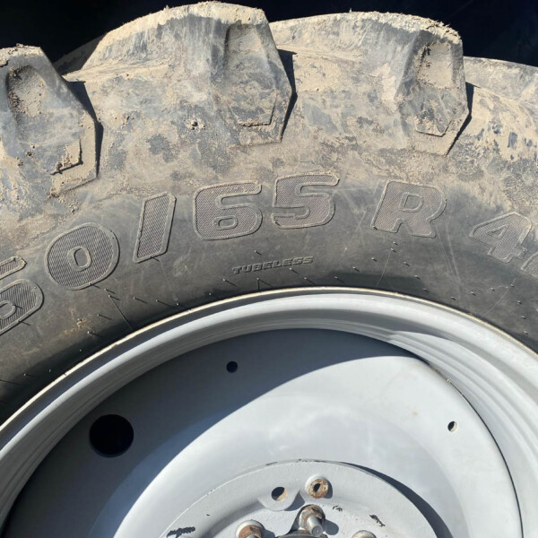 Close-up of a muddy off-road tire with chunky tread and a steel wheel rim visible at the bottom.