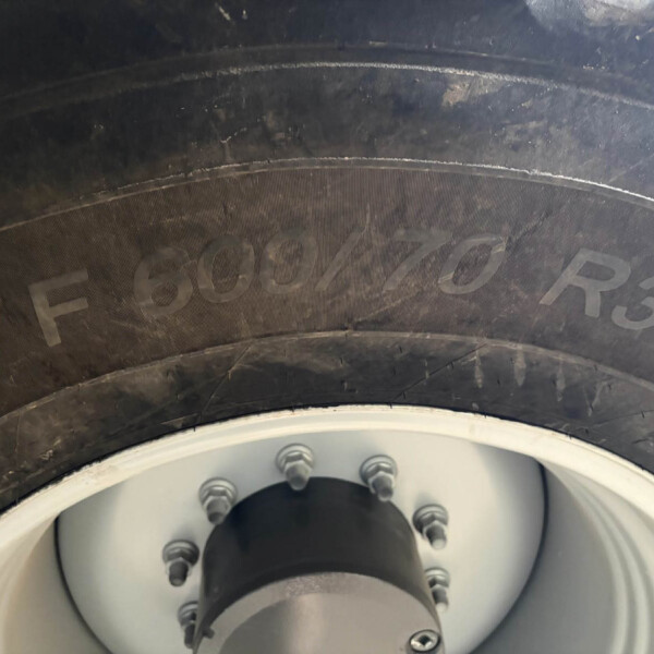 Close-up of a car tire mounted on a silver wheel, showing lug nuts and wheel hub detail.