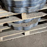 Stack of blue interlocking foam floor mats on wooden pallets in a dusty storage area