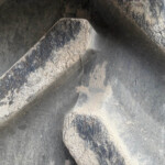 Close-up of a weathered rock surface with a diagonal ridge and dark, gray tones.