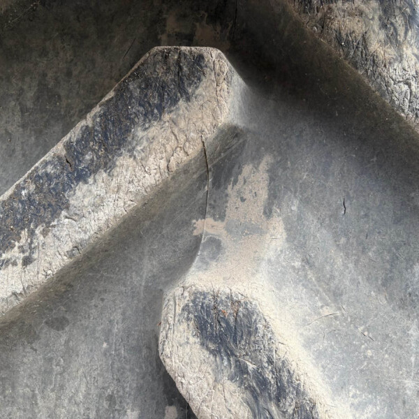 Close-up of a weathered rock surface with a diagonal ridge and dark, gray tones.