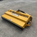 Yellow McConnel mower attachment resting on a concrete surface, with hydraulic hoses and safety decals visible.