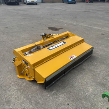 Yellow industrial equipment attachment resting on a paved parking lot, with cars lined up in the background.