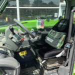 Cockpit of a bright green Merlo machine with steering wheel, joystick, and control panel visible inside the cab.