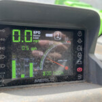 Merlo machine dashboard showing zero speed with green digital readouts and warning indicators.