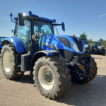 Blue New Holland tractor in a row of large farm tractors on a sunny day